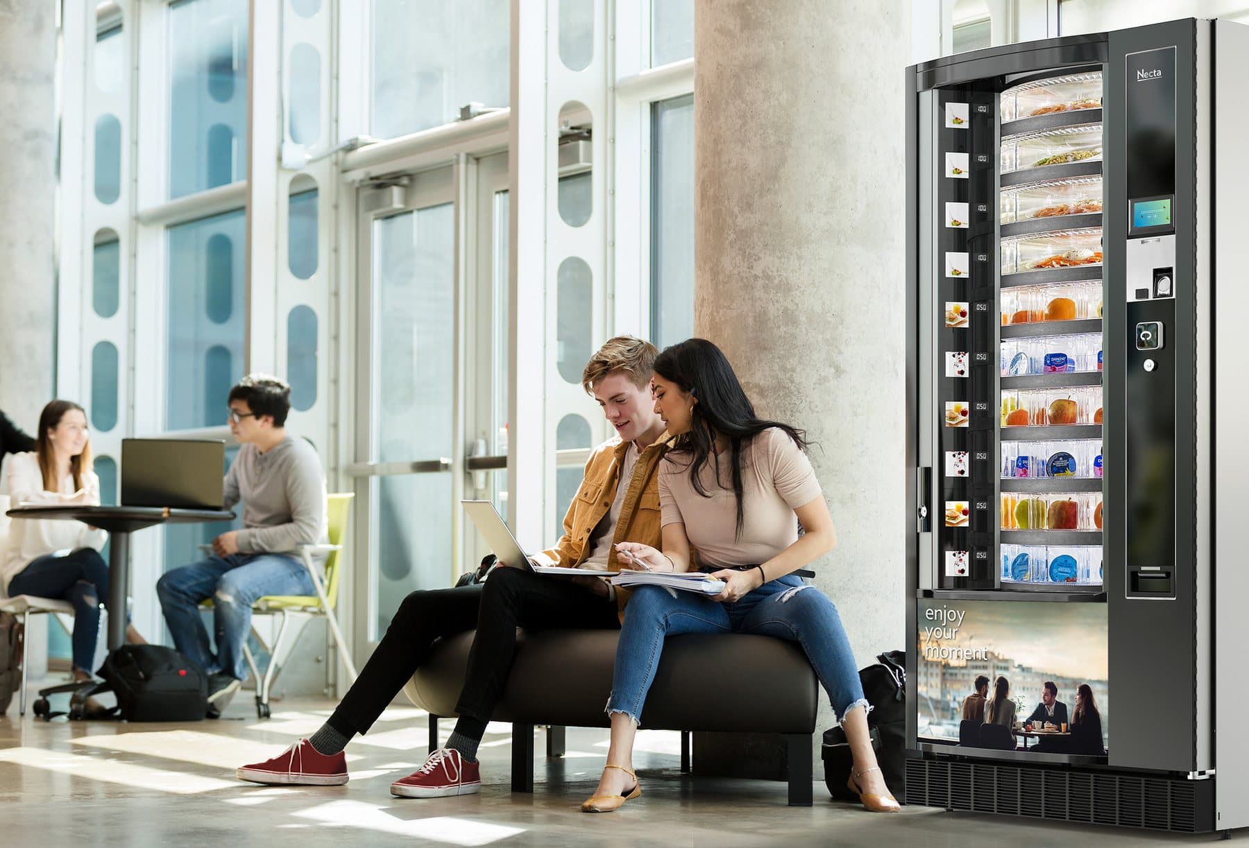 Students beside a Necta Gusto Drum fresh food machine in a bright atrium