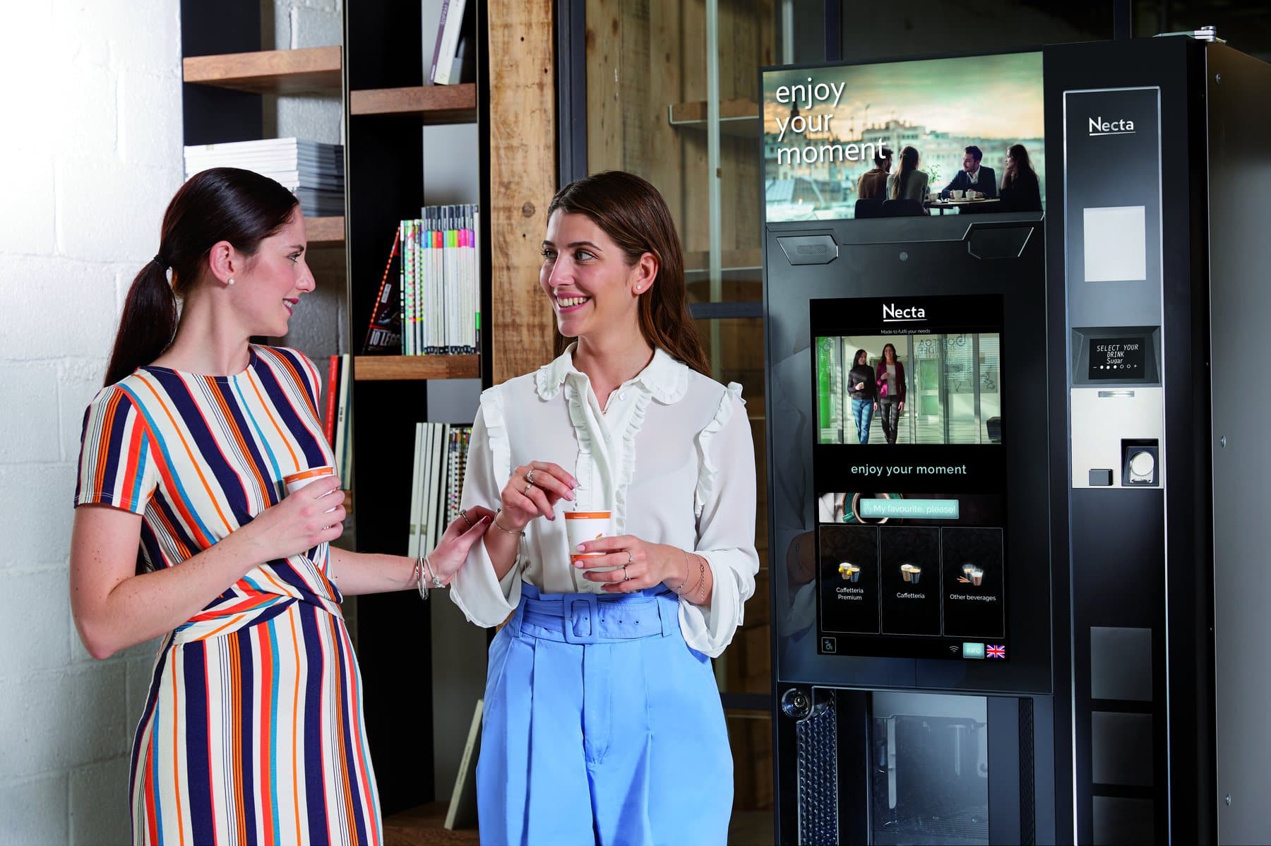 Two colleagues with coffee beside a Necta Barista 1000 Touch