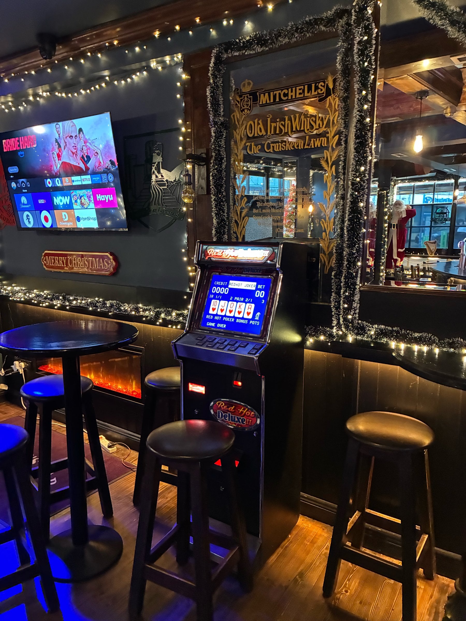 Red Hot Deluxe II poker machine in a pub decorated with Christmas lights, beside a fireplace