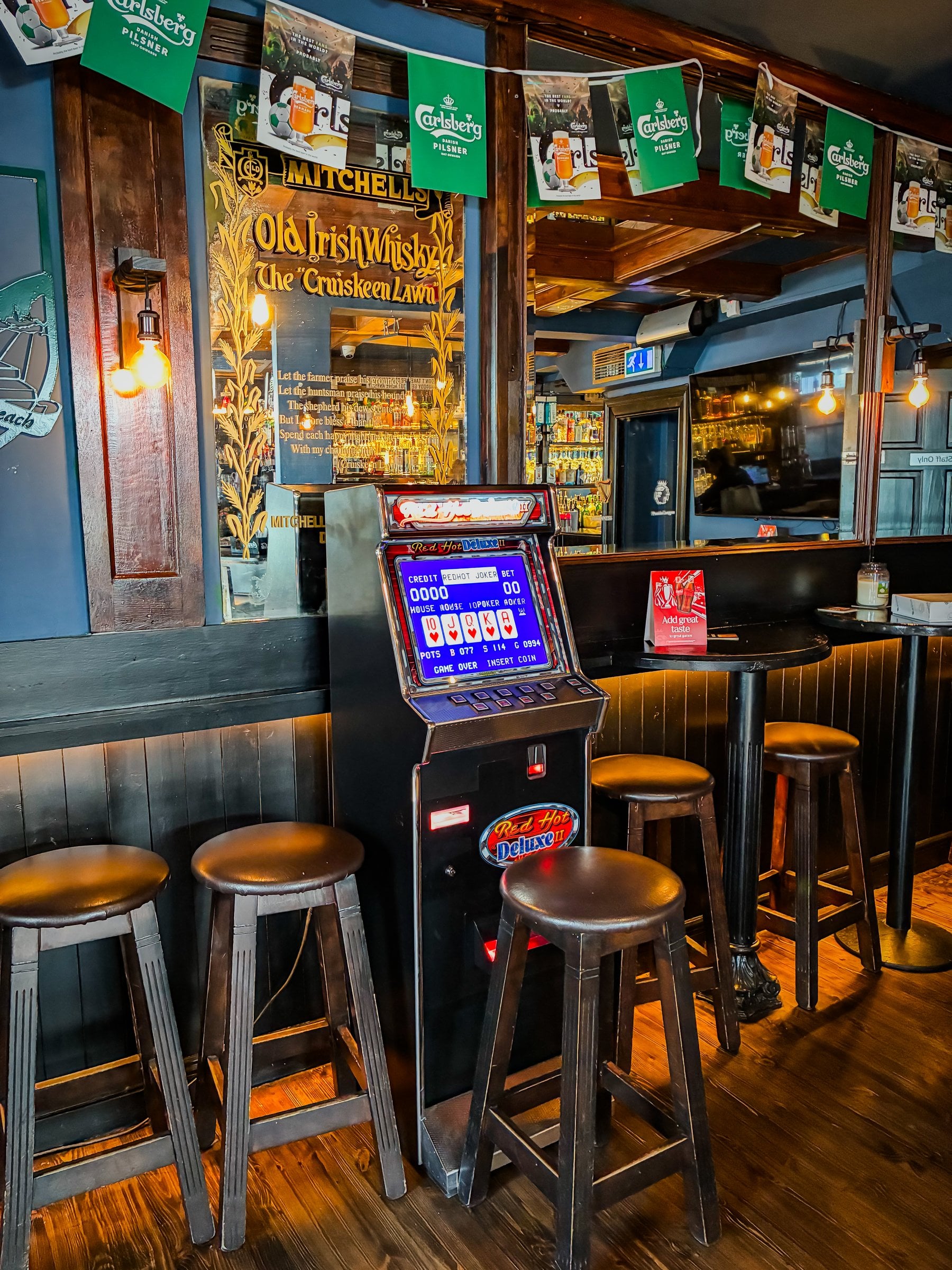 Red Hot Deluxe II poker machine in a pub, beside a Mitchell’s Old Irish Whisky mirror and Carlsberg bunting